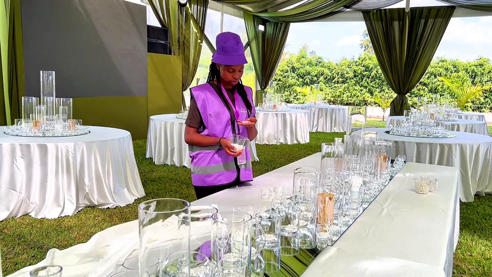 A Purple Heart team member in a purple vest laying out glass vases along a long table