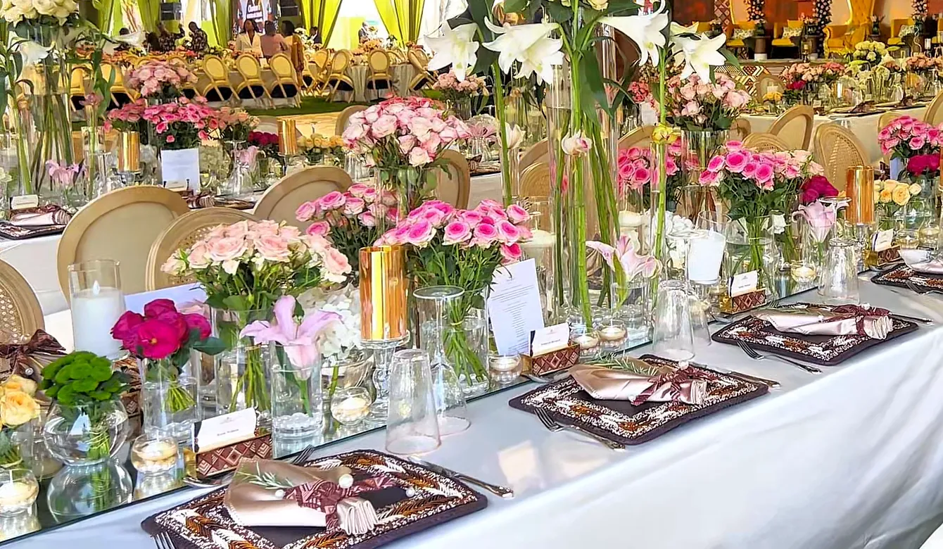Pink roses, lilies and hydrangeas down the centre of a guest table