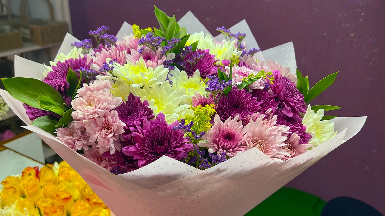 A mixed chrysanthemum bouquet taking shape at the shop counter