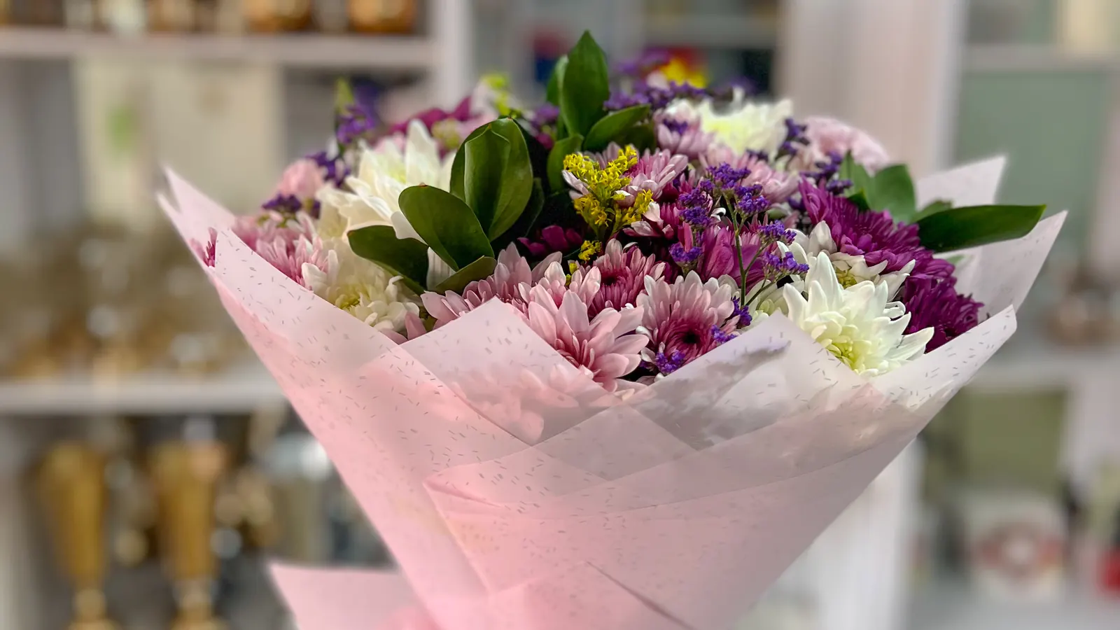 A finished bouquet in pink wrap standing in a vase