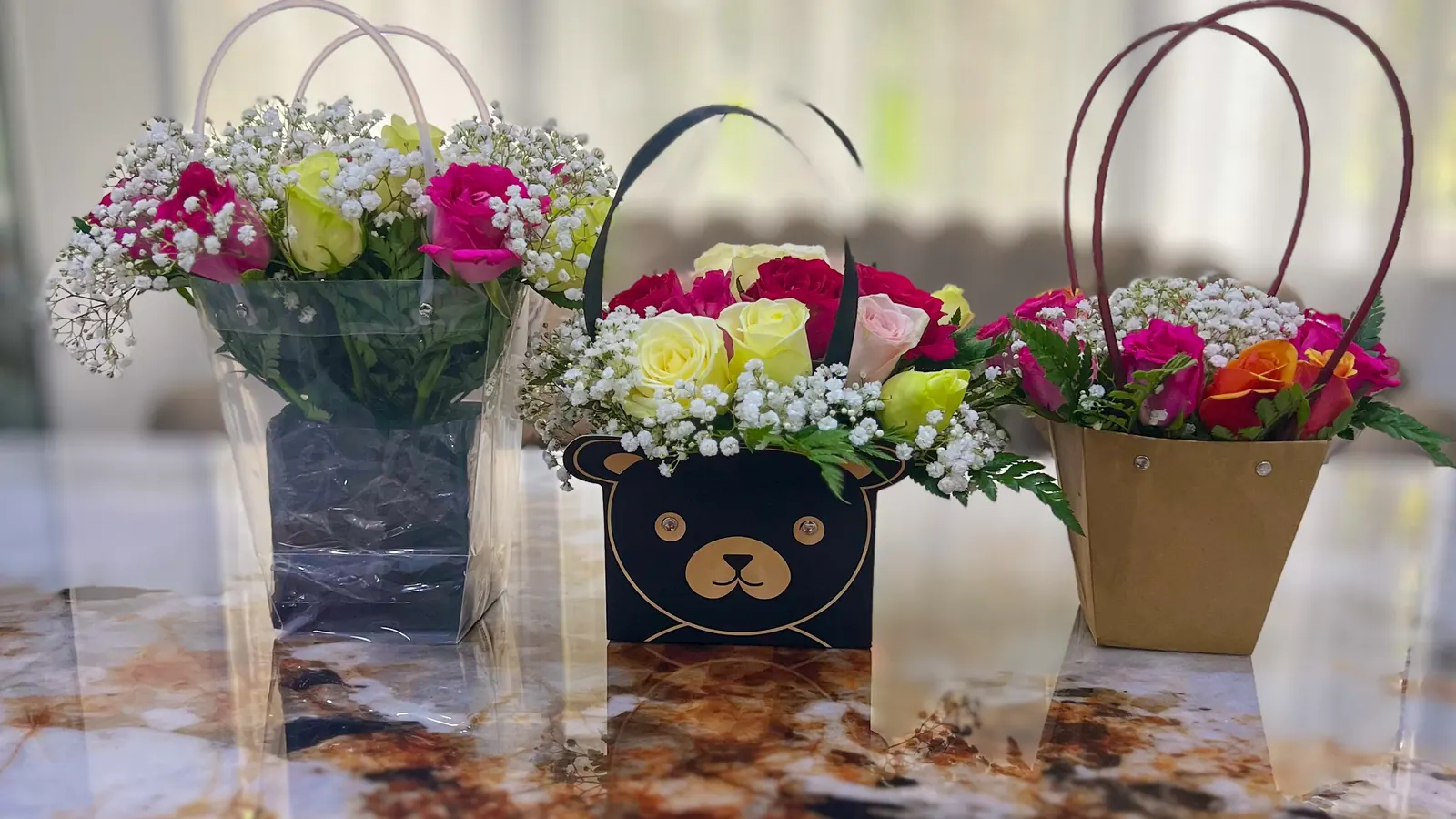 Three flower gift bags: clear, bear-faced and kraft, filled with roses