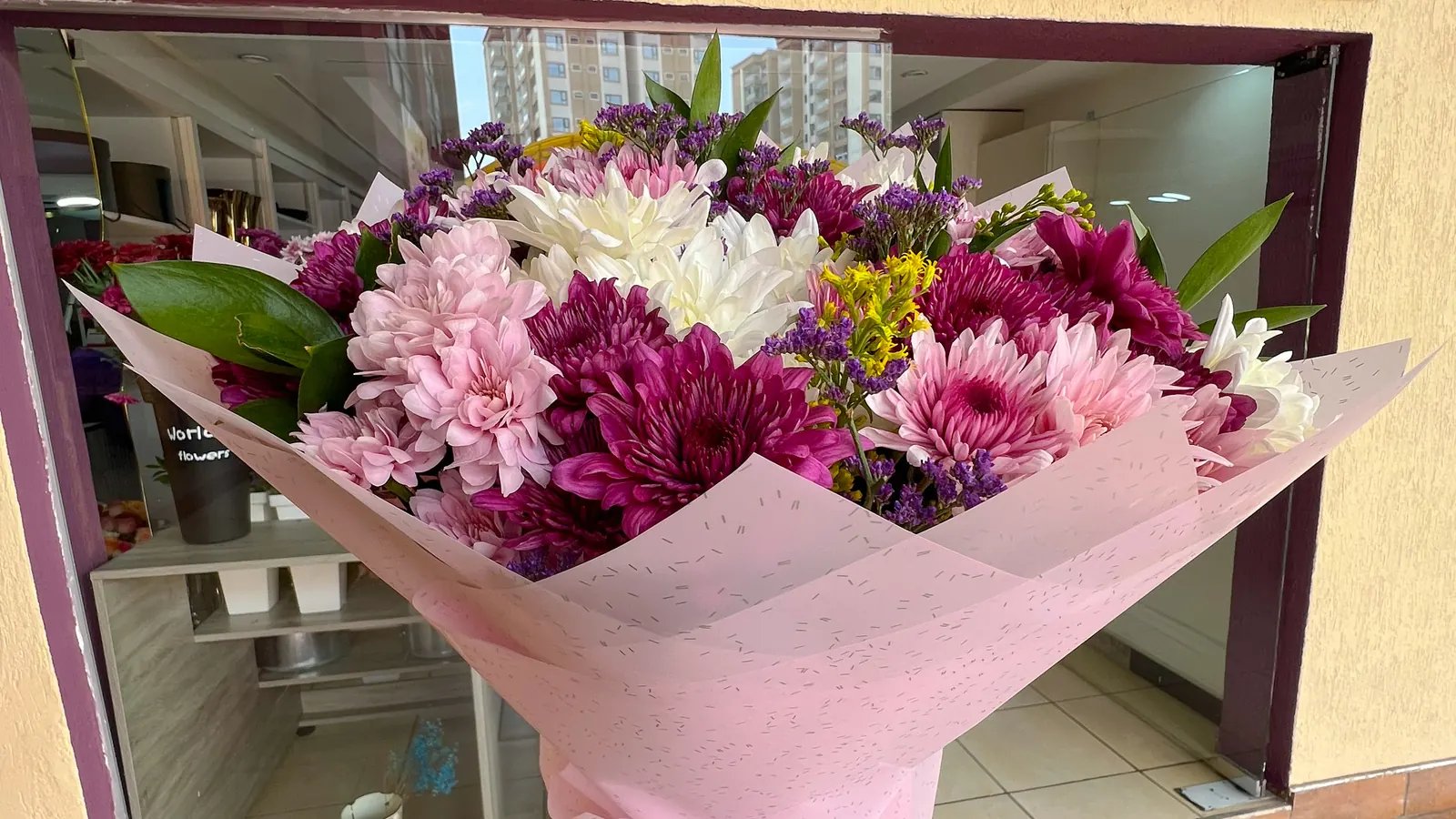 A wrapped bouquet held up outside the Purple Heart shop front