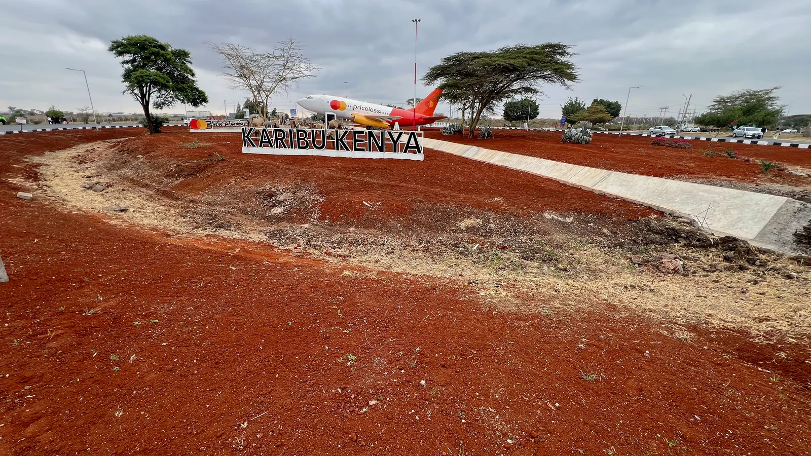 The JKIA approach before planting: red-soil beds around the Karibu Kenya sign