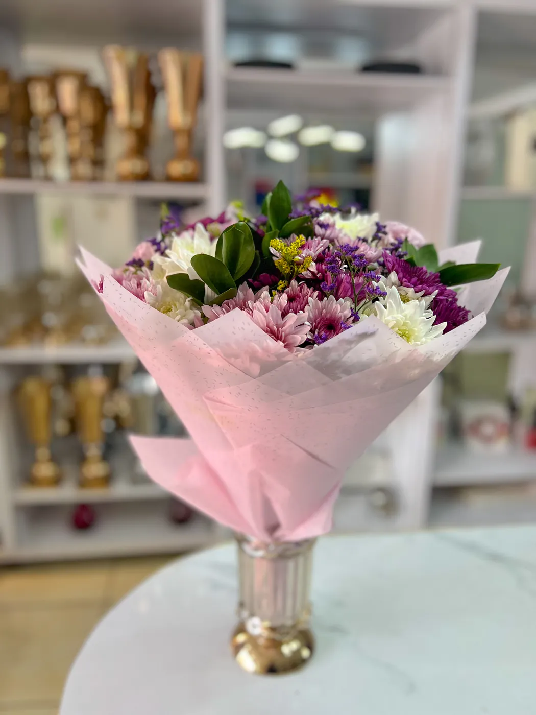 A pink-wrapped chrysanthemum bouquet in a vase at the shop