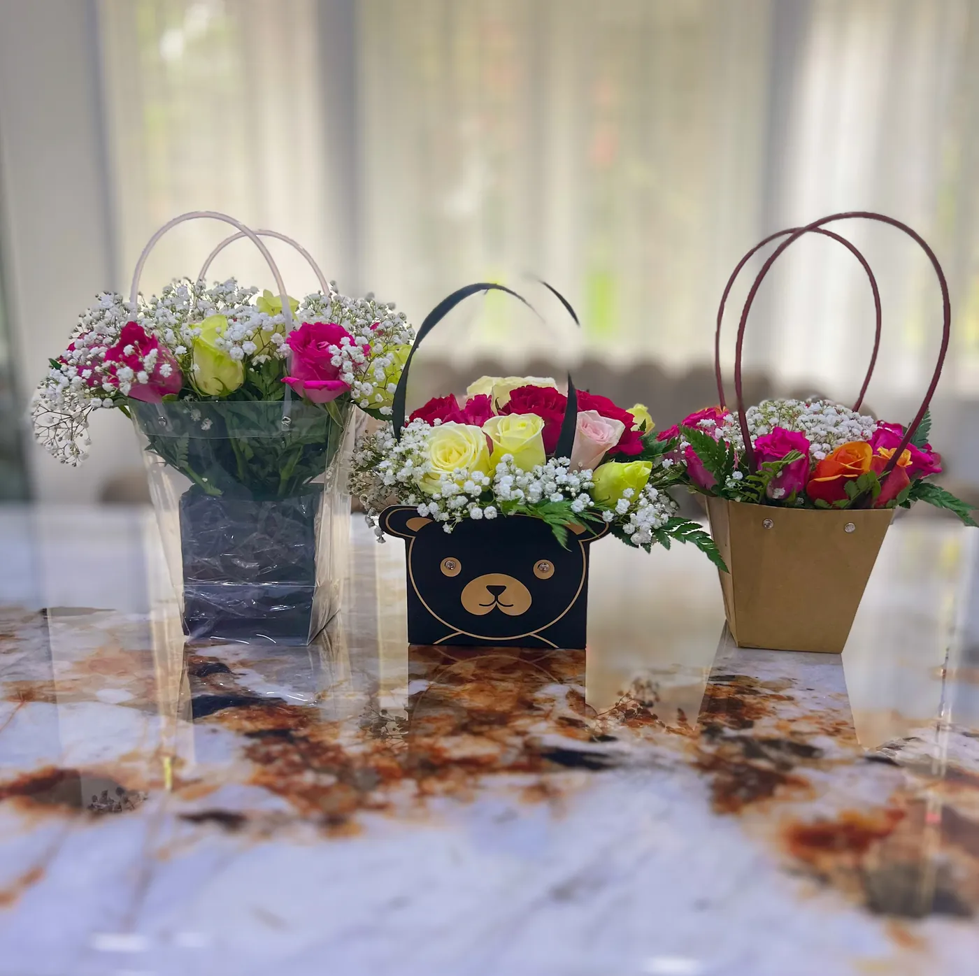Three flower gift bags filled with roses and gypsophila