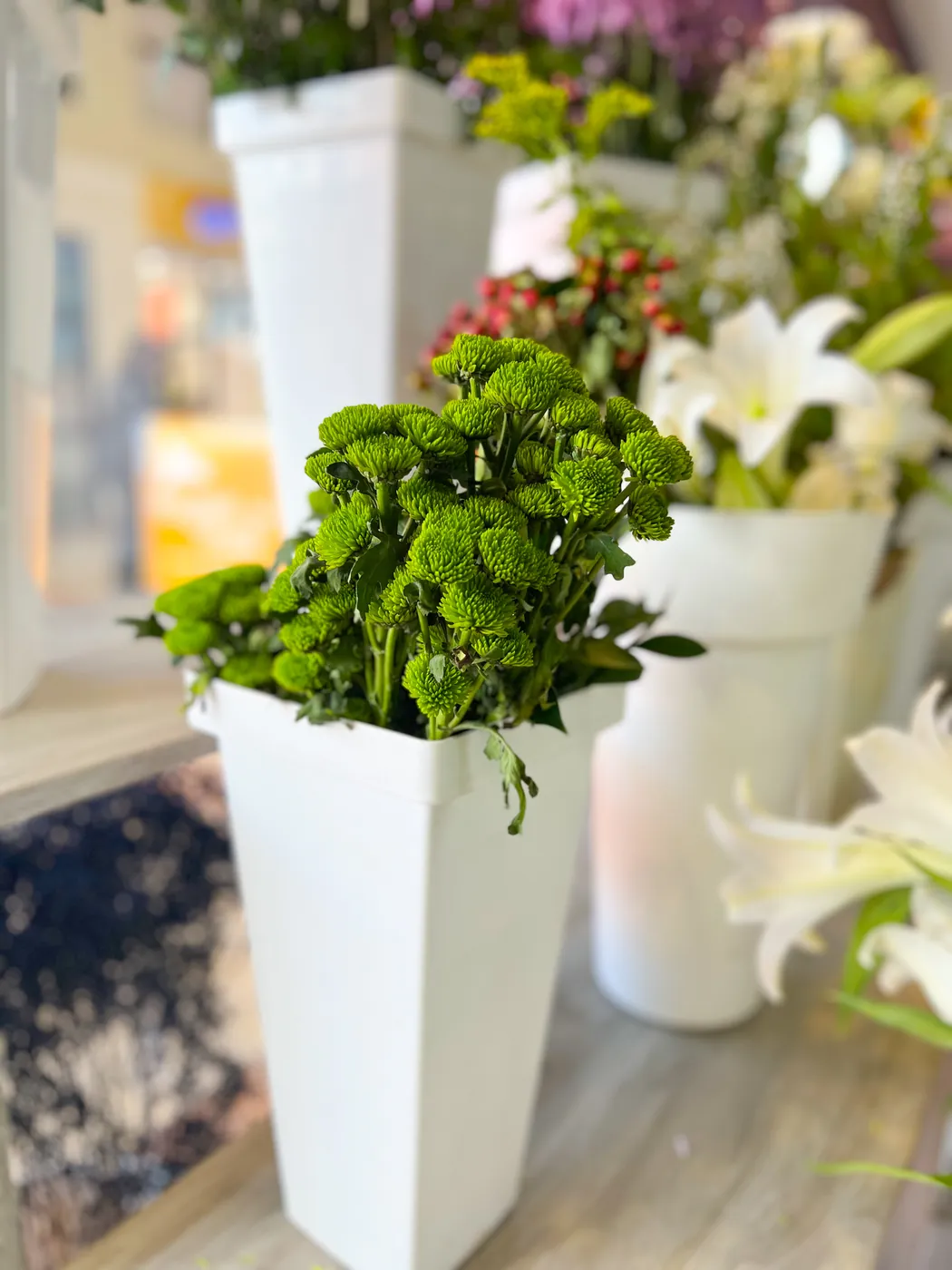 Green button chrysanthemums and white lilies on display