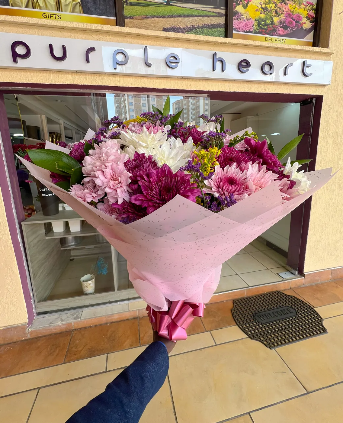 A wrapped bouquet held up outside the Purple Heart shop front